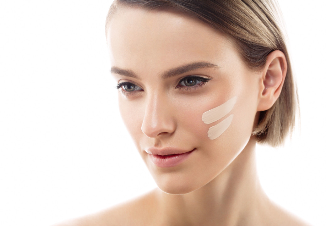 Skin tone cream lines on woman face. Beautiful woman portrait beauty skin healthy and perfect makeup. Studio shot. Isolated on white.